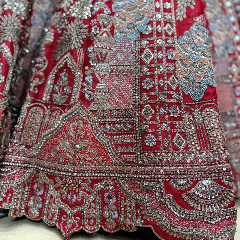 Red bridal lehenga fabric detail with dense silver embroidery and border trim
