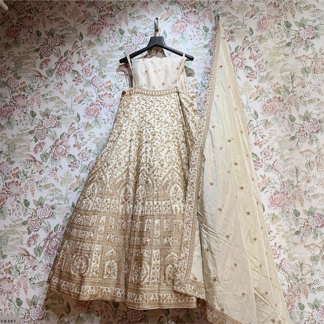 Ivory lehenga on hanger with gold zari detailing and sheer dupatta