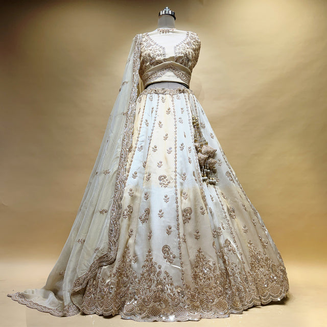 Off-white bridal lehenga skirt with gold beadwork and ornate hem, with sheer dupatta