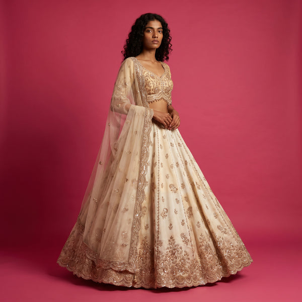 Off-white wedding lehenga with gold bead embroidery, flared skirt and embroidered bodice