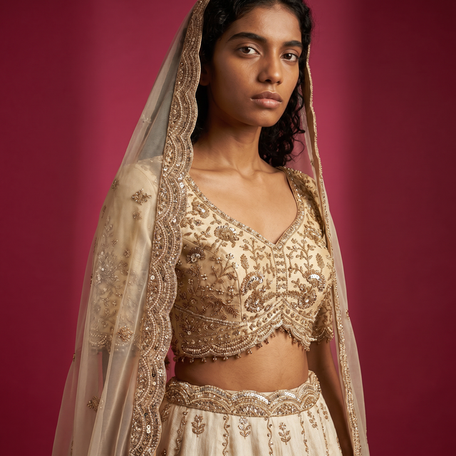 Off-white embroidered blouse and lehenga with gold bead trim and sheer dupatta drape