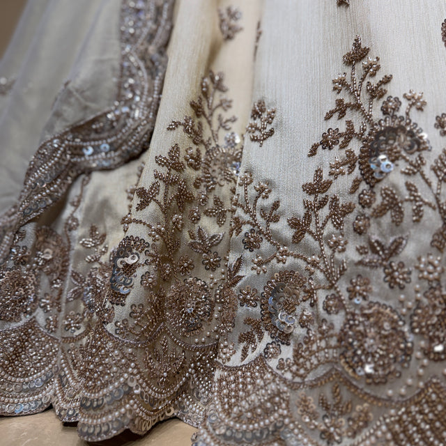 Close-up of off-white lehenga fabric with gold and silver-toned bead embroidery