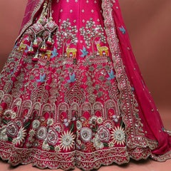 Close-up of rani pink lehenga: spotted deer under flowering trees, blue birds and a hem band of cream and blush roses