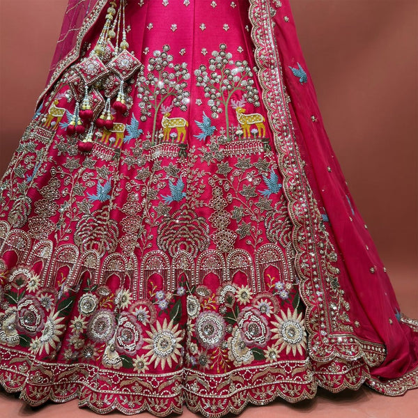 Close-up of rani pink lehenga: spotted deer under flowering trees, blue birds and a hem band of cream and blush roses