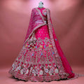 Rani pink raw silk bridal lehenga with deer, bird and jharokha embroidery, multicolour rose hem and double dupatta