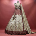 Ivory tissue silk lehenga with red cutdana chevron yoke, vine embroidery and deep red scalloped hem