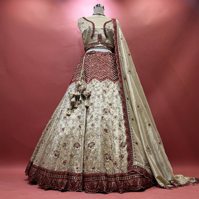 Ivory tissue silk lehenga with red cutdana chevron yoke, vine embroidery and deep red scalloped hem