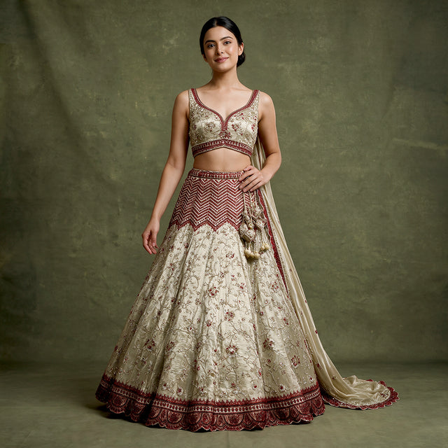 Ivory lehenga with red cutdana work and embroidered border on sleeveless top