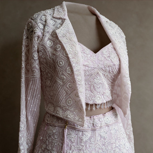 Close-up of beaded jacket with notched collar, handwork blouse with bead fringe and waistband on baby pink net