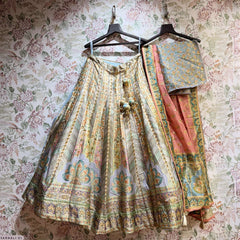 Lehenga set on hangers: cream pleated skirt with teal motifs, pink and teal dupatta