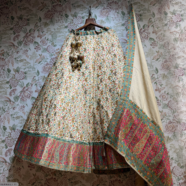 Floral off-white lehenga hanging with green and red embroidered hem and wide border