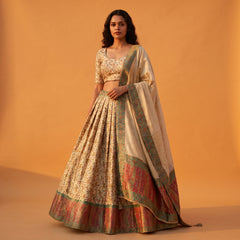 Off-white Banarasi lehenga with floral weave, multicolor border and matching blouse, dupatta drape.