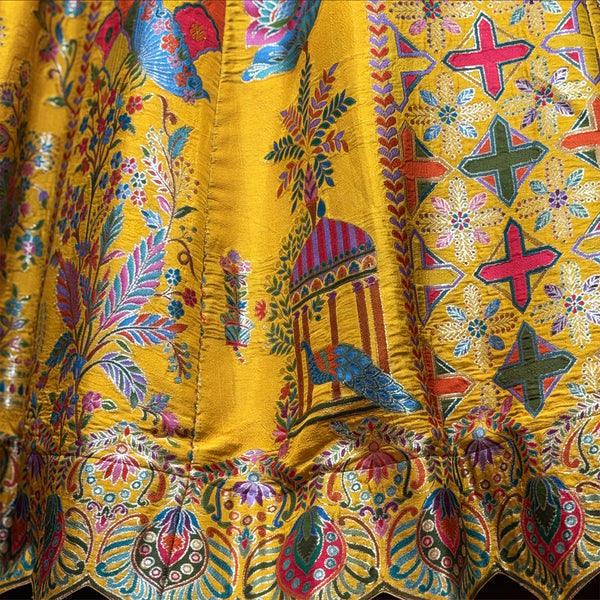 Banarasi-style silk lehenga fabric close-up, yellow with blue and red cross prints