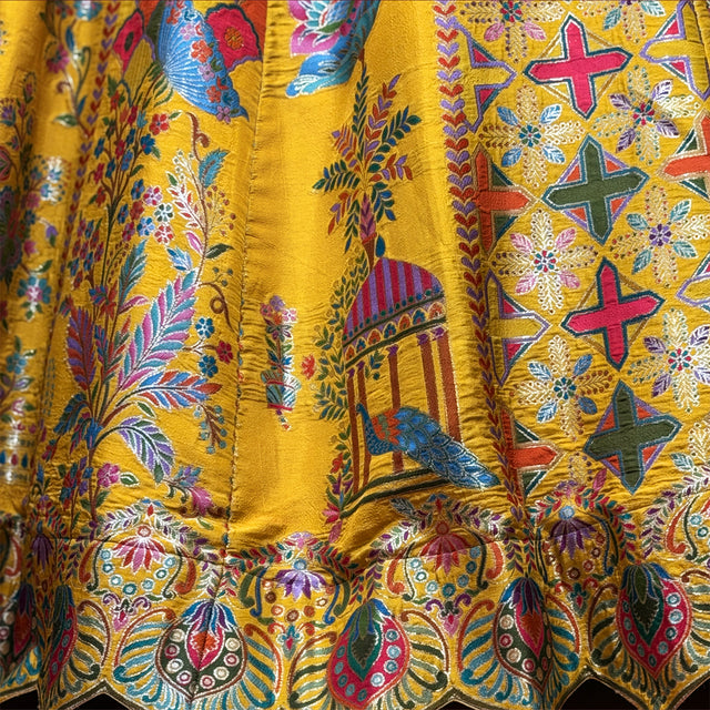 Banarasi-style silk lehenga fabric close-up, yellow with blue and red cross prints