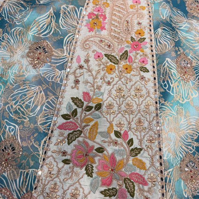 Embroidered fabric panel with floral motifs and gold details on a sky-blue base