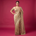 Model in a champagne gold viscose silk saree with a scalloped bead and cutdana border along the pallu and drape, and a matching stitched gold blouse with embroidered sleeve cuffs
