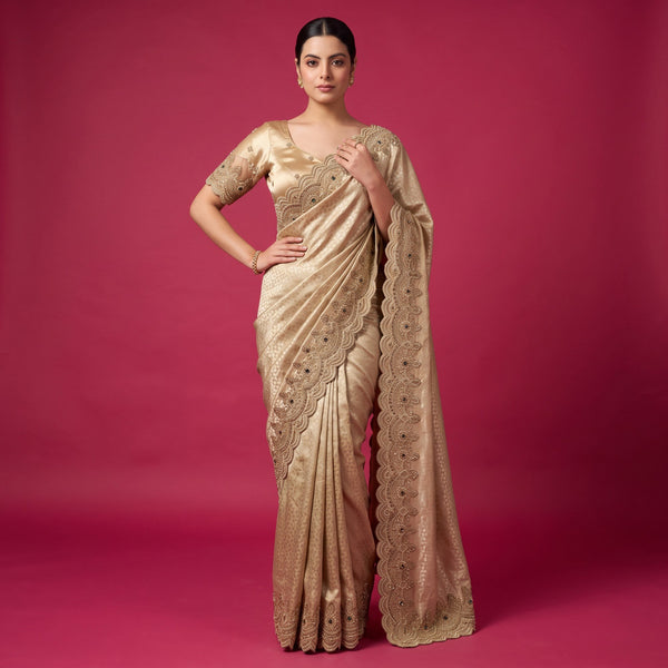 Model in a champagne gold viscose silk saree with a scalloped bead and cutdana border along the pallu and drape, and a matching stitched gold blouse with embroidered sleeve cuffs