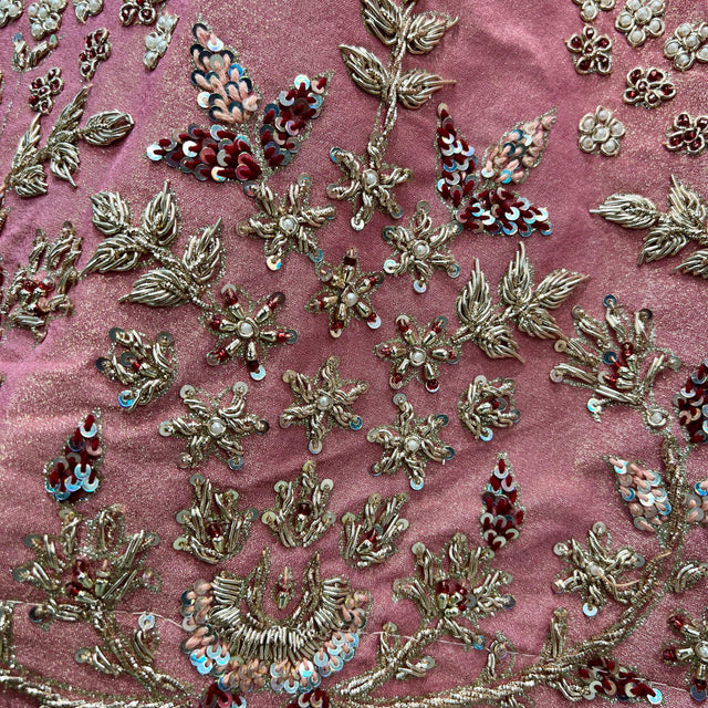 Close-up of pink fabric with gold zardosi motifs, silver beads, and teal sequin accents