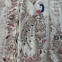 Close-up of zardozi embroidery on ivory lehenga, blue teardrop accents and florals