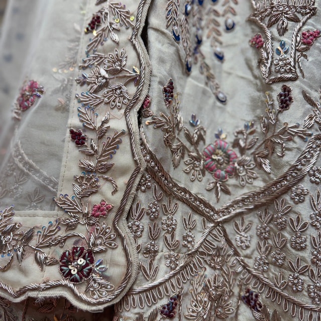 Close-up of ivory lehenga fabric with zardozi peacock and floral bead embroidery