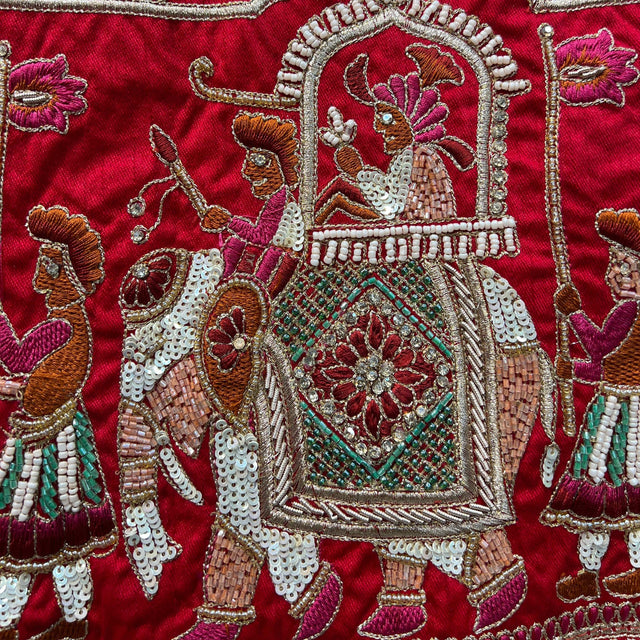 Red bridal lehenga with ornate beaded medallion design and decorative border embroidery.