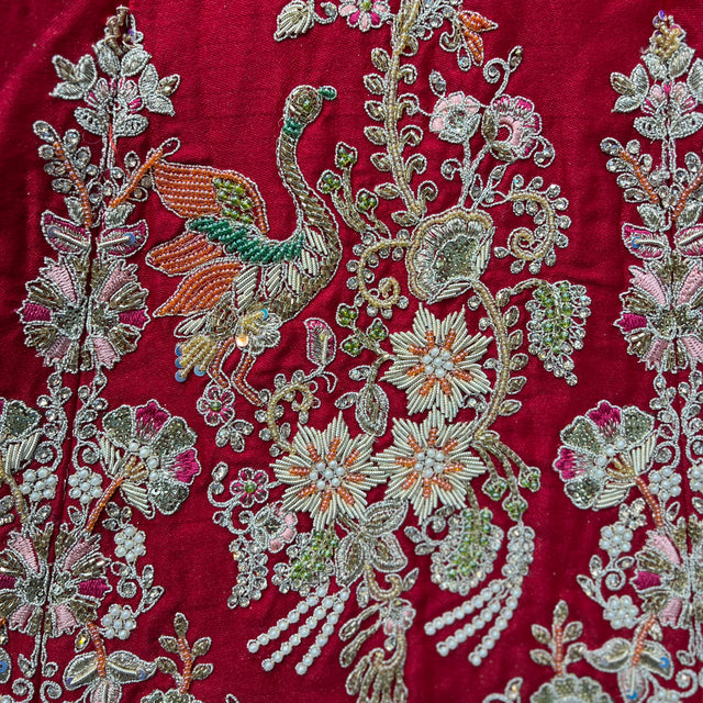 Close-up red lehenga fabric with silver, green & white beadwork and zardosi