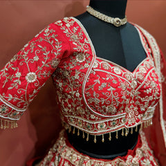 Close-up of a red sweetheart-neck blouse with floral vine embroidery, pearls and beaded tassel fringe on the hem and sleeve