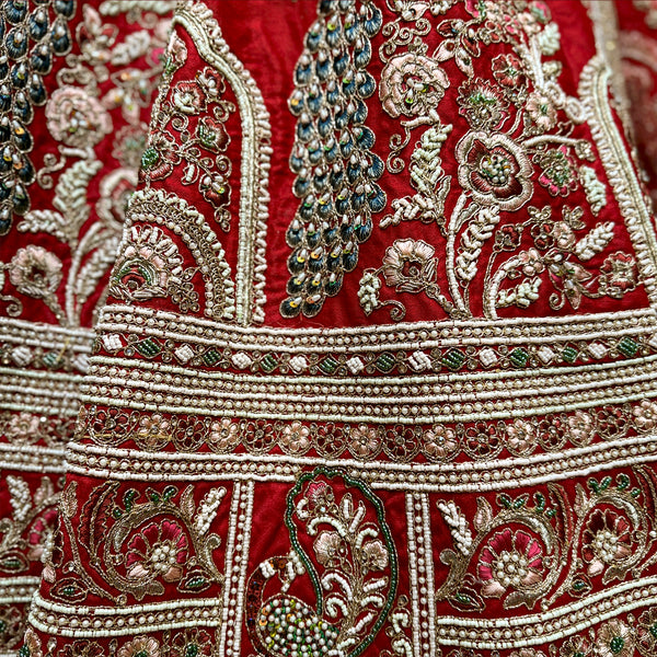 Close-up of red lehenga embroidery with gold trim and green-and-silver beadwork