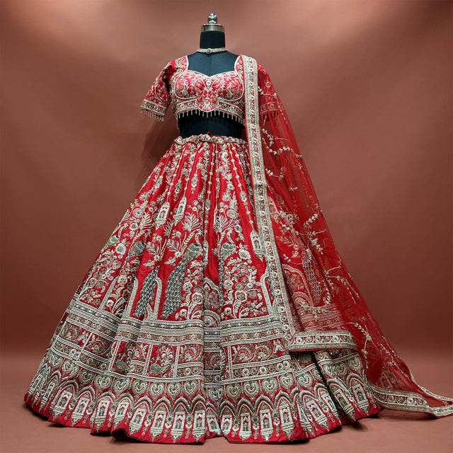 Red bridal lehenga set on a mannequin with peacock motifs, arched hem and net dupatta