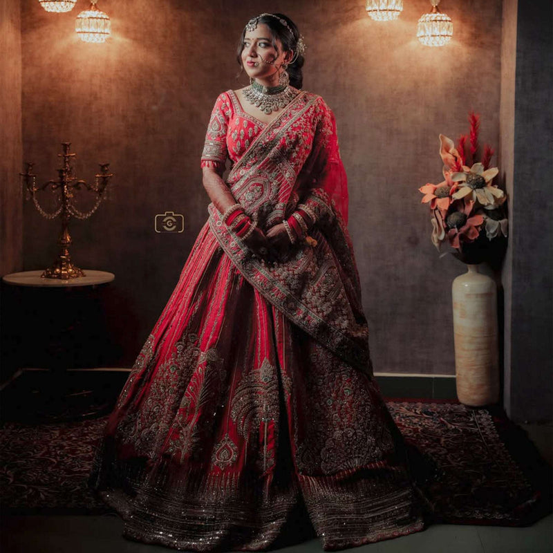 Red bridal lehenga with flared skirt, ornate silver-gold embroidery and border trim