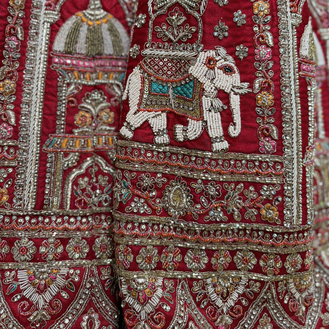Close-up of red lehenga embroidery with jeweled elephant motif in silver thread