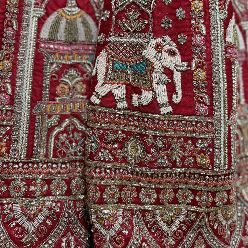 Close-up of red lehenga embroidery with jeweled elephant motif in silver thread