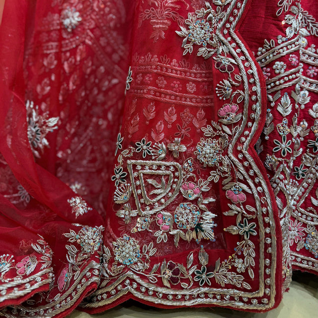 Red lehenga hem panel with silver-toned zardosi scrollwork, beads, and floral sprigs