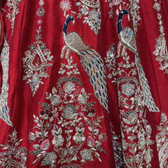 Red silk lehenga fabric with detailed silver and multicolor peacock and floral embroidery