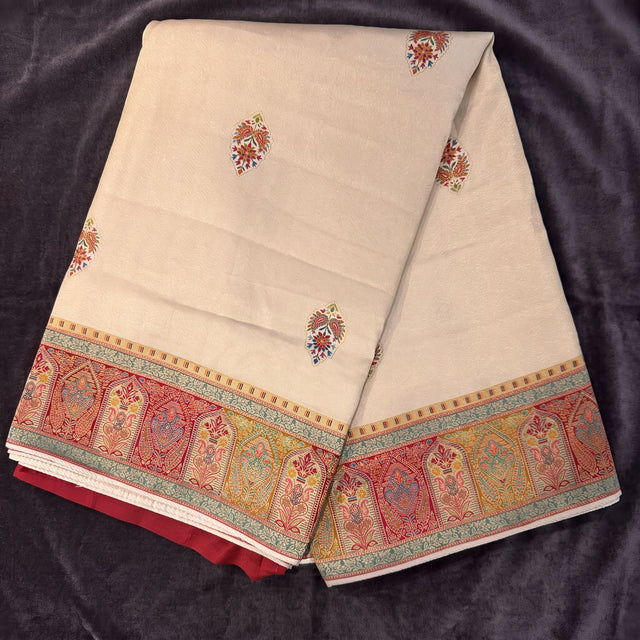Cream silk saree with scattered buta motifs and red kani-style border on fold