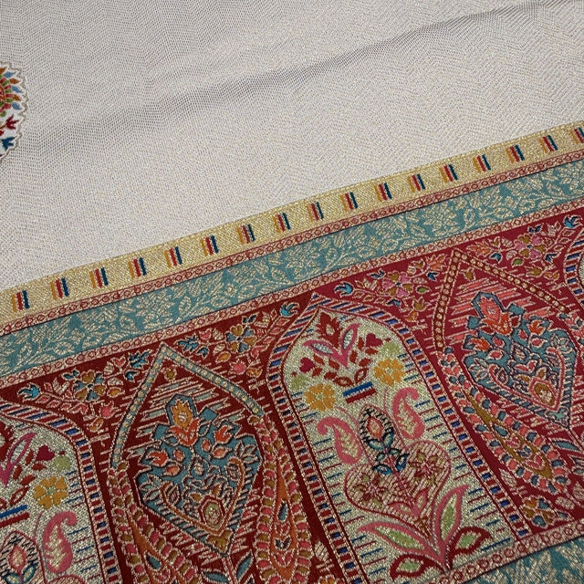 Saree border close-up with geometric arch pattern in red, teal, gold and cream