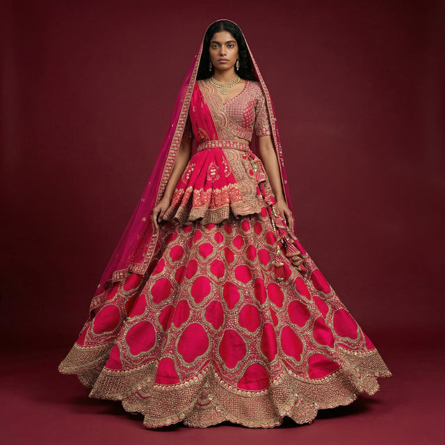 Full-length rani pink bridal lehenga with gold embroidered flared skirt and dupatta