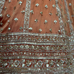 Close-up of orange lehenga skirt with silver and teal beaded embroidery stripes