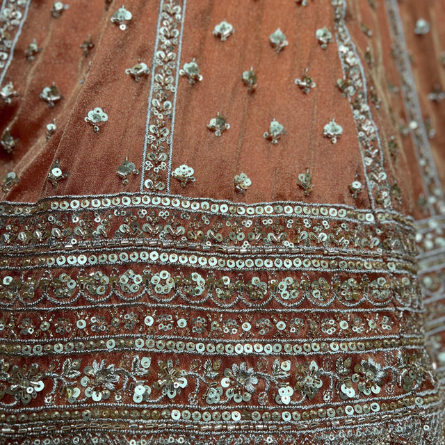 Close-up of orange lehenga skirt with silver and teal beaded embroidery stripes