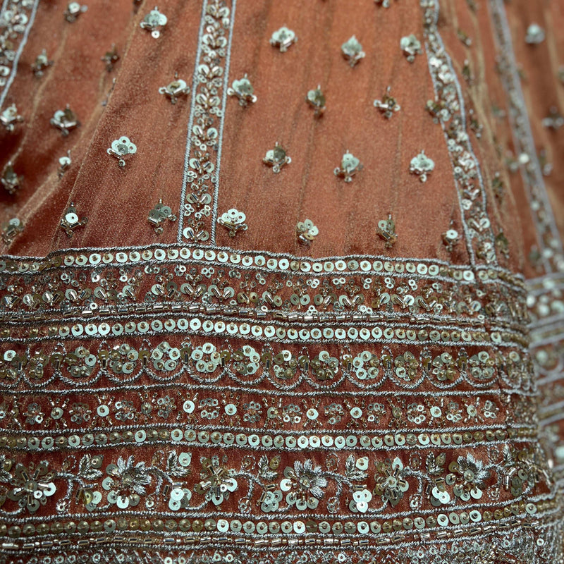 Close-up of orange lehenga skirt with silver and teal beaded embroidery stripes