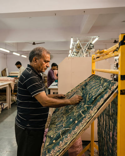 A JMS Studio team member inspecting an embroidered lehenga by hand before it ships