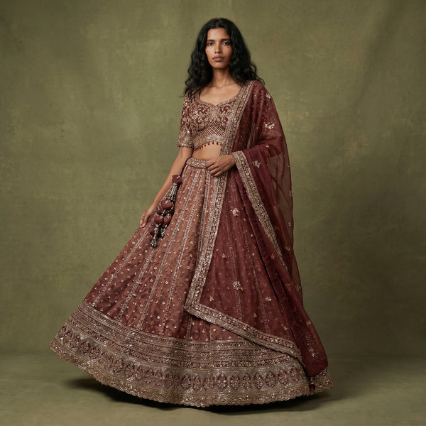 Rust-orange designer lehenga with gold border and intricate handwork, flared skirt
