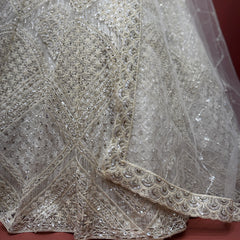 Close-up of off-white net lehenga with resham and stone beadwork along hem