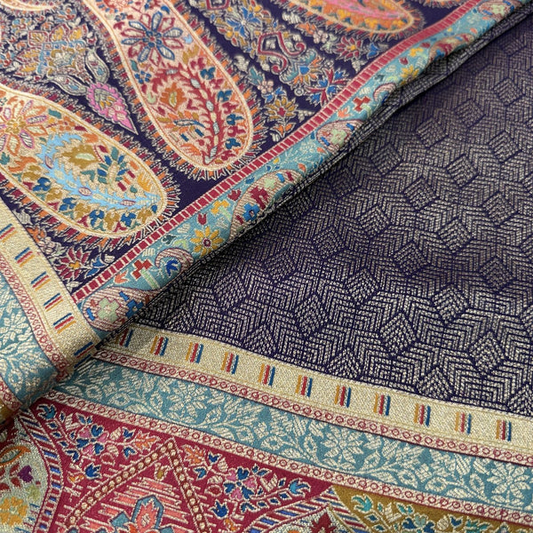 Silk saree close-up with teal and orange paisley border and dark navy woven panel