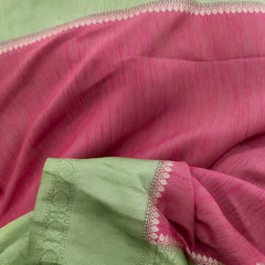 Close-up of pink saree fabric with pista green border and zari detailing