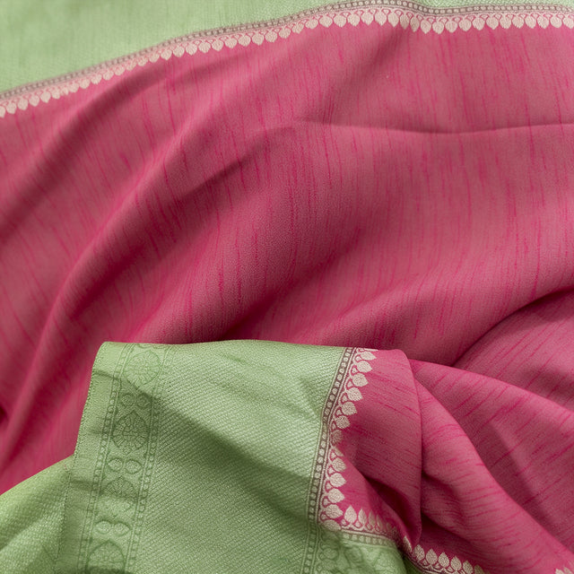 Close-up of pink saree fabric with pista green border and zari detailing