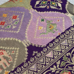 Purple saree close-up with geometric animal motifs and embellished border