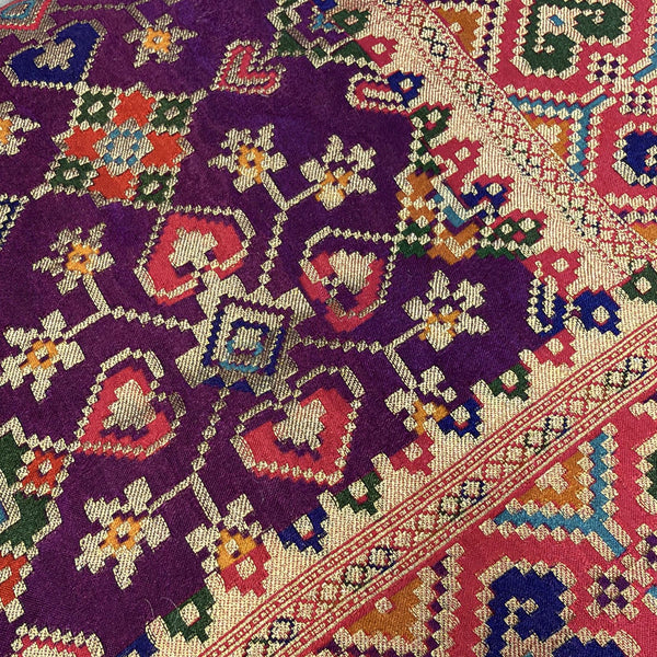 Close-up of purple patola diamond motifs on viscose fabric with red border