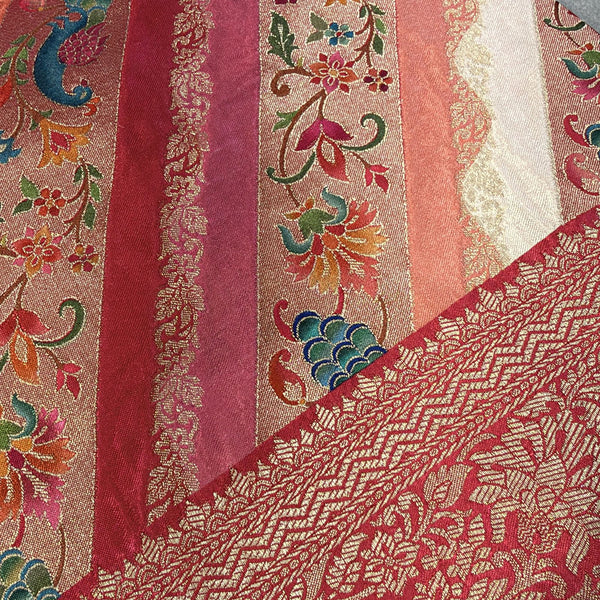 Red saree fabric close-up with leheriya stripes, floral and peacock prints, zari work