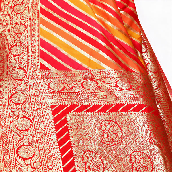 Close-up of red and orange silk saree fabric with woven paisley and stripe motifs